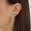 Diamond teardrop earring on woman's ear with emerald earrings and diamond ear cuff