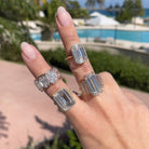 Woman wearing diamond emerald cut rings.