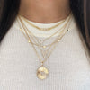 Woman wearing pave love necklace above layered yellow gold and pave necklaces