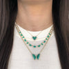 Diamond & malachite butterfly necklace layered with yellow gold & emerald necklaces on woman's neck