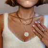 Woman wearing pearl & diamond butterfly necklace with yellow gold chain link necklaces