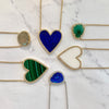 Emerald, malachite, lapis, and pearl necklace collection on yellow gold chains, against marbled background