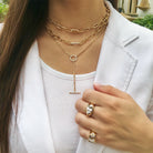 Woman wearing pear shape ring with another gypsy ring and yellow gold chain link necklaces from collection