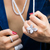 Model wearing flower ring with baguette diamond necklaces and white gold pave rings