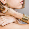 Woman wearing bead hoop earrings with chunky yellow gold jewelry