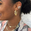 Woman wearing butterfly hoop earrings with large pave ear cuffs and yellow gold necklaces