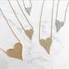 Diamond small heart necklace in white, rose, and yellow gold against a marbled background