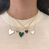 Diamond & turquoise heart necklace on woman's neck layered with larger diamond heart necklaces in white, malachite, and lapis
