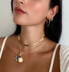 Woman wearing Disc Star Necklace with yellow gold herringbone choker necklace and hoop earrings