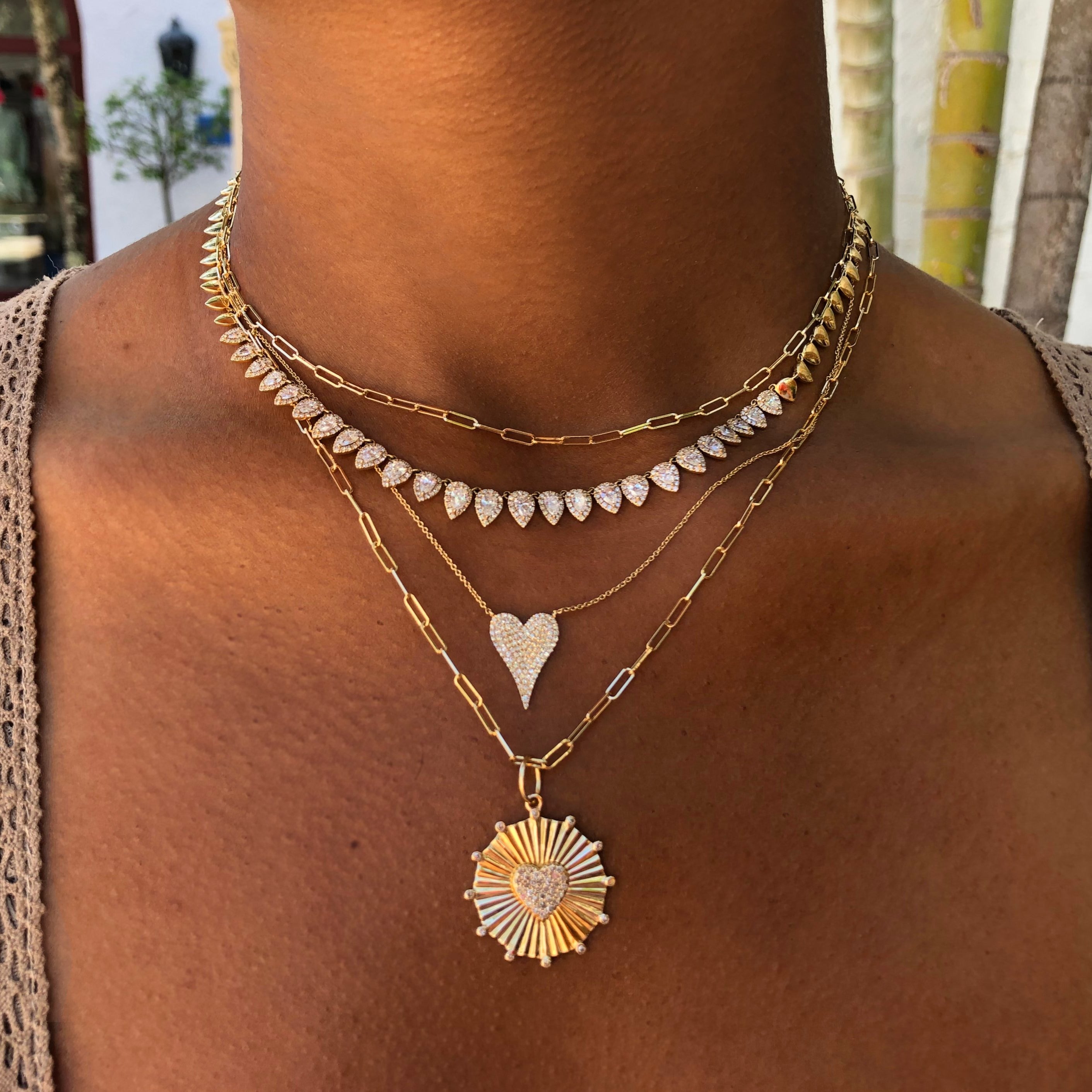 Woman wearing paperclip chain layered with pave necklaces
