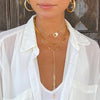 Woman wearing chain lariat layered with herringbone and handcuff necklace, all yellow gold