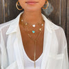 Woman wearing chain lariat layered with chain link charm necklaces, all yellow gold