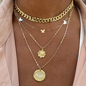 Cuban link chain layered with delicate yellow gold necklaces