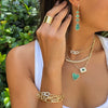 Woman wearing wide band ring with other yellow gold and emerald jewelry