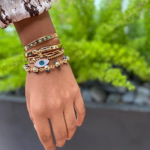 Eye chain bracelet worn with yellow gold bangles and chain link bracelets