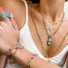Yellow gold chain link necklace and bracelet collection worn layered together with turquoise accents,  including turquoise & diamond heart necklace
