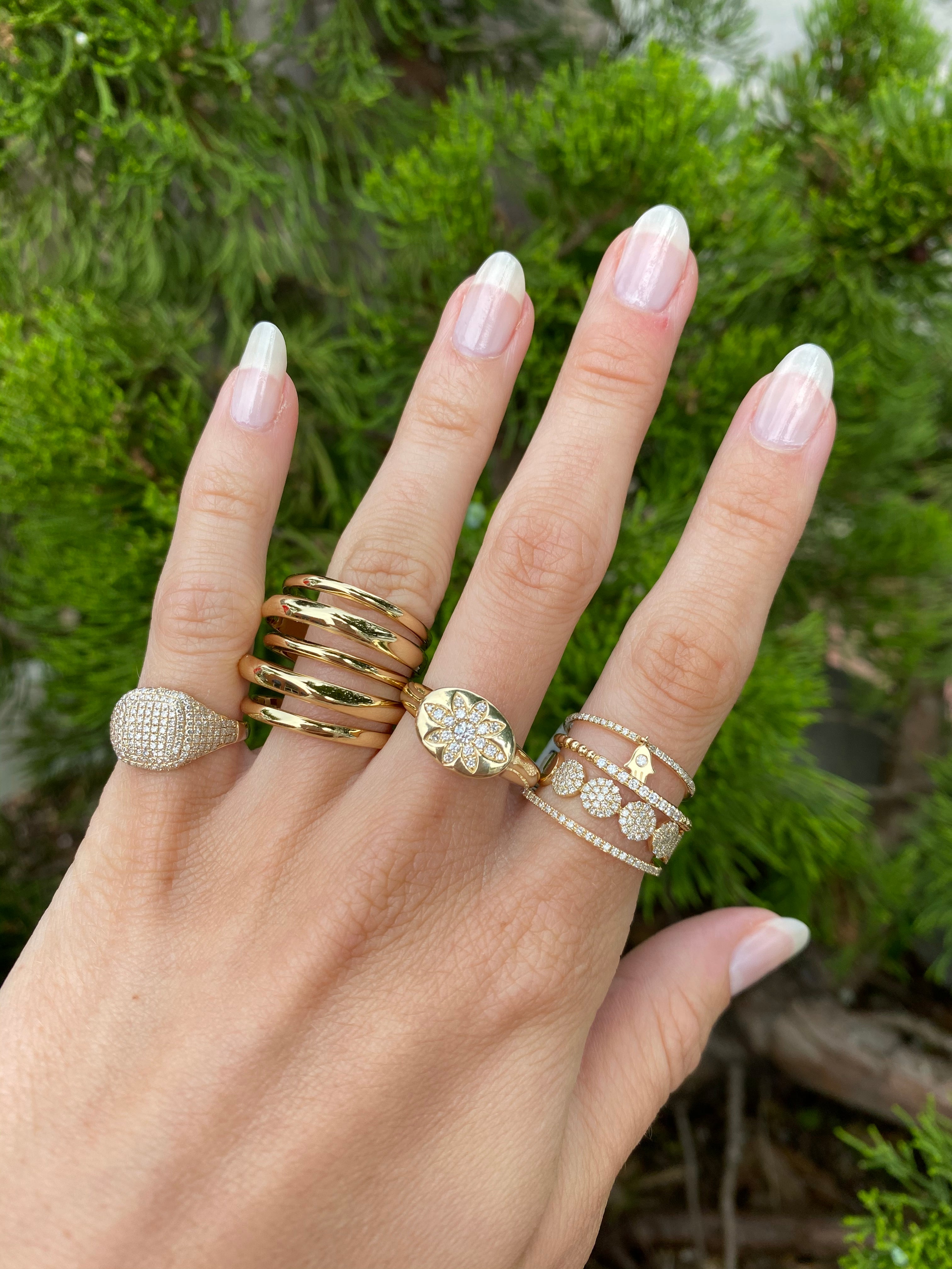 Diamond eternity band on woman's hand paired with other yellow gold and diamond pave rings