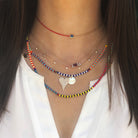 Woman wearing evil eye choker with layered colorful necklaces