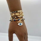 Oval link bracelet worn on wrist with yellow gold and charm bangles