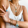 Starburst charm necklace worn layered with shorter chains and paired with chain link gold bracelets