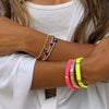 Woman wearing evil eye bead bracelet with neon pink and yellow gold bracelets