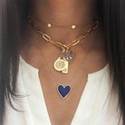 Multi charm necklace worn layered with yellow gold chains