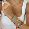 Woman wearing yellow gold chain link necklace with colorful bracelet collection