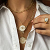Woman wearing yellow gold chain layered with other pendants from necklace collection