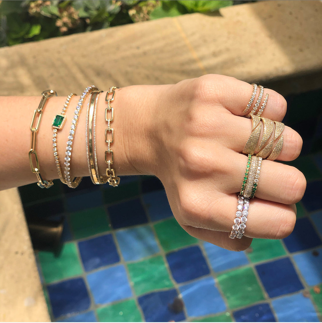 Woman wearing diamond coil ring with diamond pave rings and yellow gold chain link bracelets