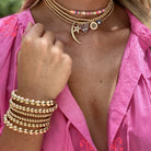 Woman wearing beaded coil bracelet with yellow gold beaded charm necklaces