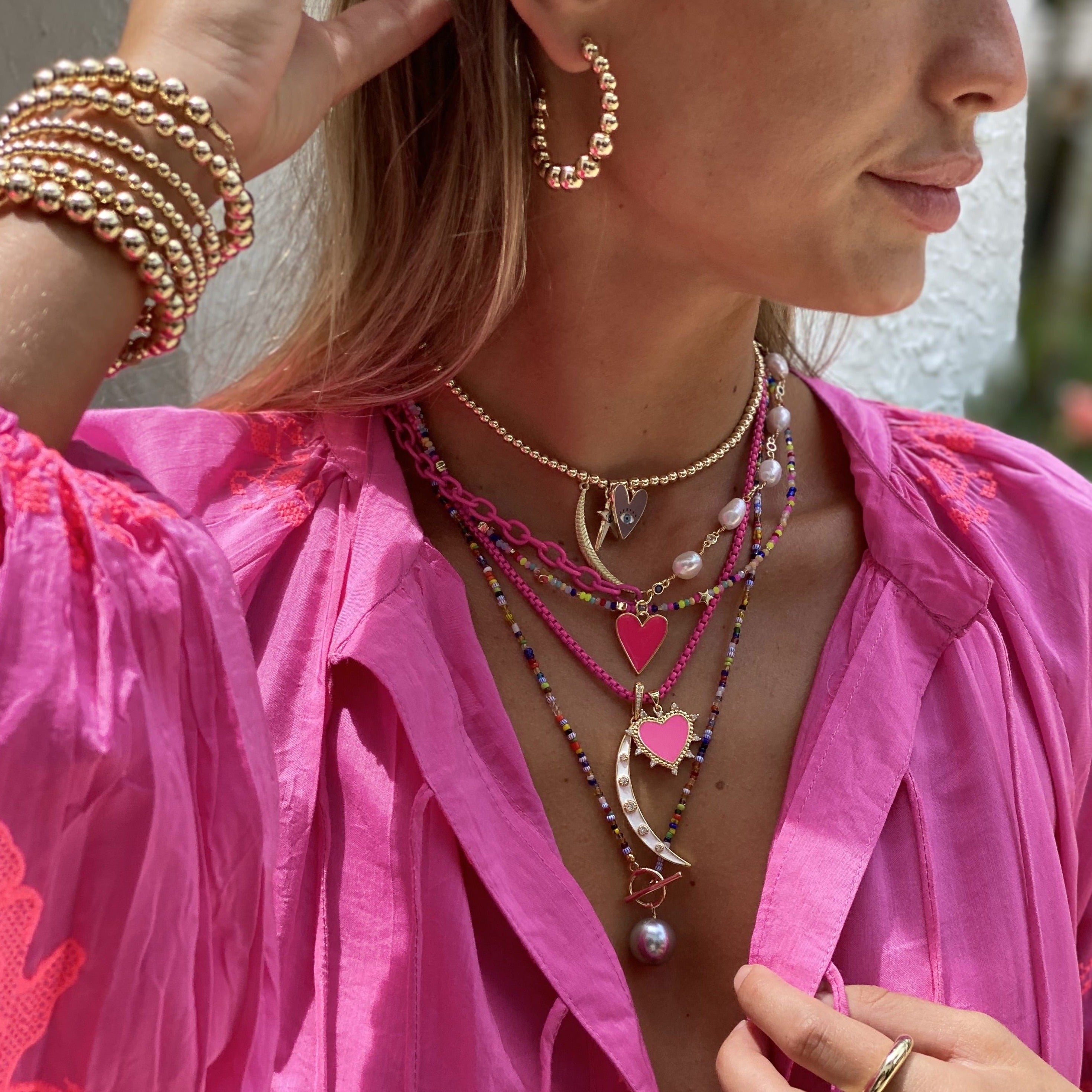 Woman wearing beaded hoop earrings with matching beaded bracelet and other yellow gold jewelry