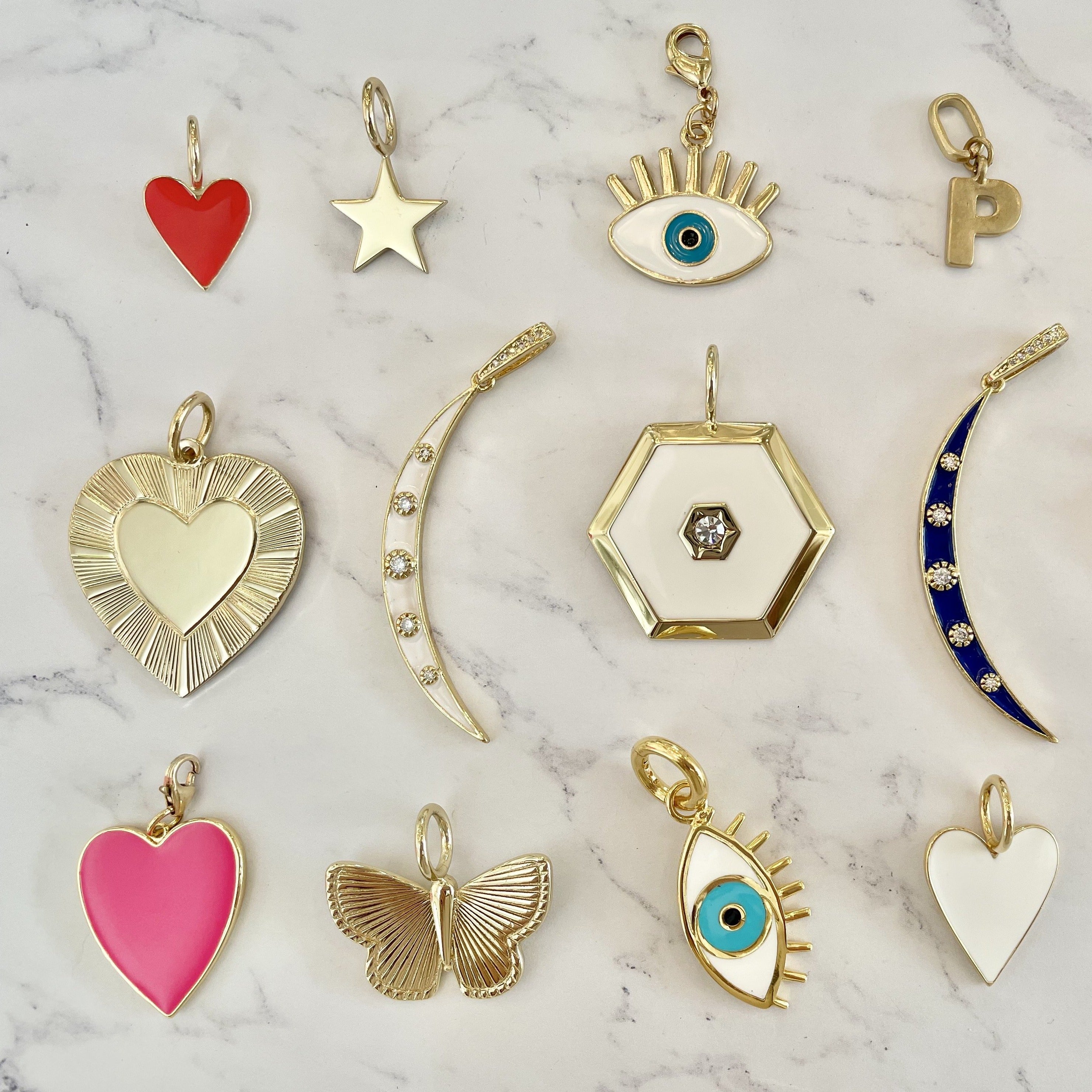 Yellow gold charm collection against a white marbled background