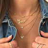 Butterfly station necklace displayed on woman's neck and paired with butterfly cluster necklace and yellow gold pave rings
