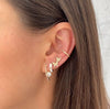 Woman wearing white huggie earrings with yellow gold pave and pearl earrings