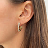Yellow gold bypass hoop earring on woman's ear