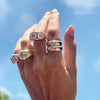 Round stone rings displayed on woman's hand with gypsy ring collection rings