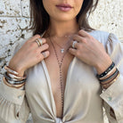 Model wearing yellow, rose, and white plated rings, bracelets, and necklaces.