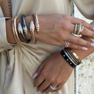 Model wearing yellow, rose, and white plated rings and bracelets.