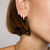 Pave huggie earrings worn beside each other on woman's ear