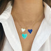 Diamond heart necklaces layered in lapis, pearl, and turquoise worn with yellow gold chains