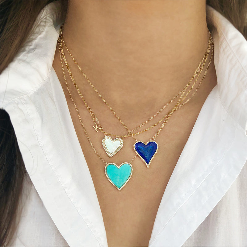 Woman wearing initial necklace with layered turquoise heart necklaces