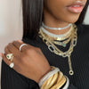 Model wearing jewelry layers of rings, bracelets, and necklaces.