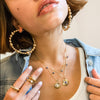 Woman wearing bead hoop earrings with yellow gold rings and necklaces