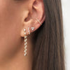 Diamond teardrop earrings on woman's ear with diamond huggie, stud, and ear cuff