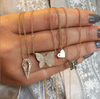Woman's hand displaying diamond butterfly necklace with other yellow gold & diamond necklaces