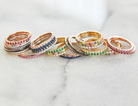 Assortment of yellow gold pave rings on marbled surface, including diamond eternity band