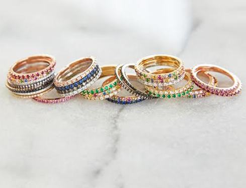 Assortment of yellow gold pave rings on marbled surface, including diamond eternity band