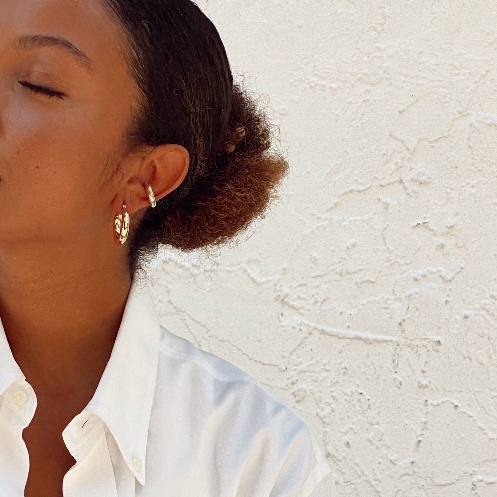 Woman wearing small thick hoops with chunky ear cuff