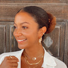 Woman wearing small thick hoops with yellow gold chunky jewelry