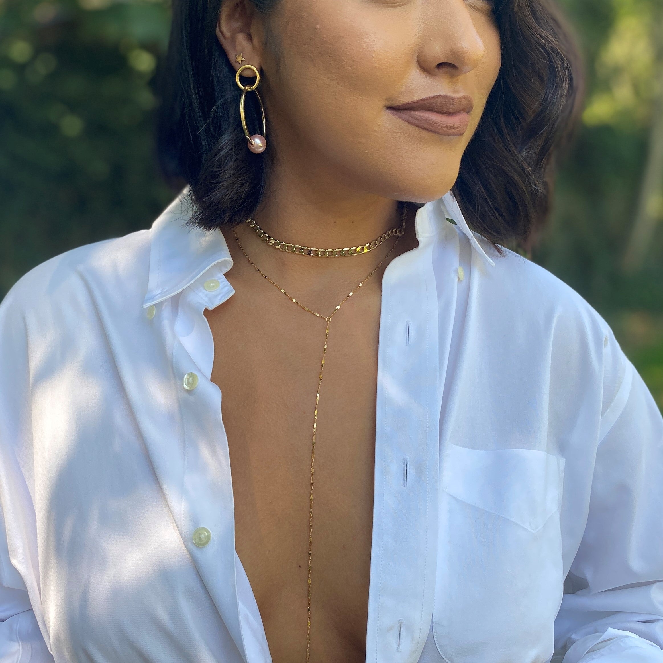 Woman wearing twinkle lariat with yellow gold pearl hoop earrings